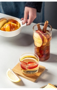 Close-up of heat-resistant stackable glass cups with fruit slices on wooden coasters