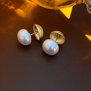 Elegant gold pearl hoop earrings with radial texture on a luxury leather surface