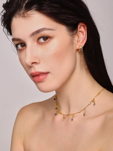 Close-up of golden bird pendant necklace and hoop earrings with colorful gemstones