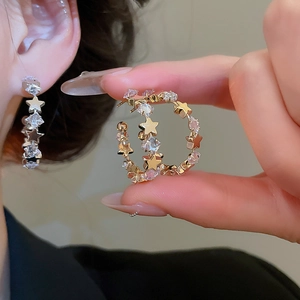 Macro shot of silver star-shaped C-earrings with sparkling cubic zirconia on a model