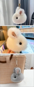 Close-up of white and grey plush bunny keychains hanging on bags with soft texture details