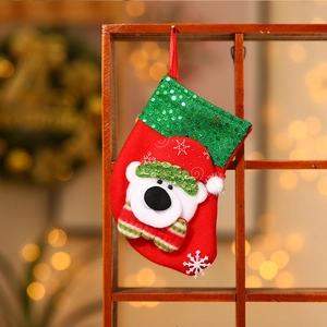 Détail d'une chaussette de Noël en feutre rouge avec paillettes vertes et un ours en 3D