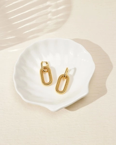 Detail of gold chain link earrings with textured spiral rings on a white tray