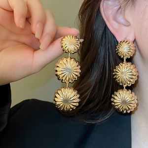 Close-up of golden three-tier ripple flower drop earrings with metallic texture