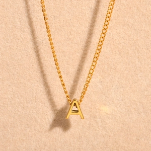 Detailed view of a gold-plated letter A pendant on a stainless steel curb chain necklace