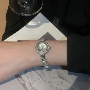 Detail of luxury rhinestone floral watch with silver bracelet worn in social setting
