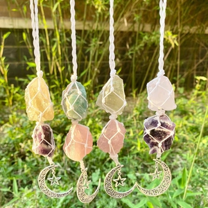 Détail de pierres d'améthyste et quartz rose brutes tissées avec des pendentifs lune et étoile
