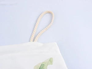 Close-up of woven rope strap and green leaf print on white holiday dress fabric
