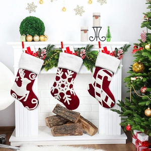 Set of 3 red embroidered velvet Christmas stockings hanging on a white fireplace mantle.