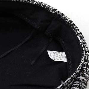 Detail of black inner lining and fabric care label for black and white tweed beret hat