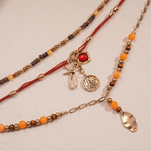 Detailed macro view of layered necklace with wood beads, metal charms and butterfly coin