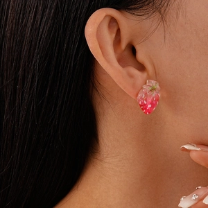 Nahaufnahme süßer rosa Erdbeer-Ohrstecker aus Harz am Ohr eines weiblichen Models