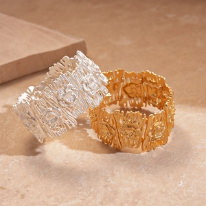 Detailed macro view of wide hollowed-out flower pattern bracelets in gold and silver