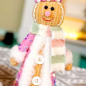 Detailed close-up of gingerbread man plush with pink sequin coat and knitted scarf