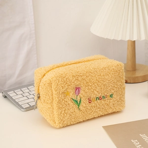 Close-up of fluffy yellow tulip plush pouch featuring sunshine embroidery and a metal zipper