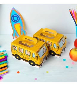 Close-up of yellow school bus paper treat box with handle and clear window on wood desk