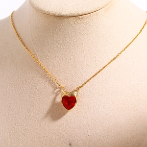 Detailed macro view of the gold heart pendant with a vibrant red zircon stone on a chain