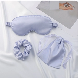 Detail shot of a lavender satin sleep set including eye mask, scrunchie, and storage pouch