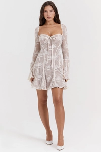 Dettaglio del mini abito in pizzo bianco con maniche a campana e scollatura a corsetto con lacci