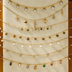 Detailed display of gold titanium steel necklaces with diverse marine and heart pendants