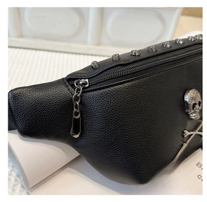 Close-up of black lychee leather chest bag featuring silver rivets and skull logo detail