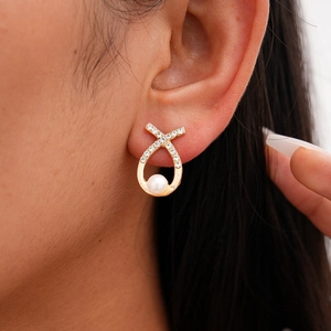 Elegant gold drop earrings with pearls and small crystals shown on a model's ear