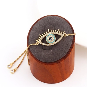 Close-up of golden evil eye bracelet with colorful cubic zirconia on wooden stand