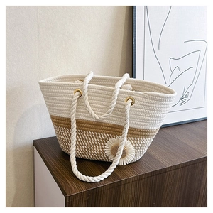 Close-up of beige straw tote bag with rope handles and white daisy floral detail