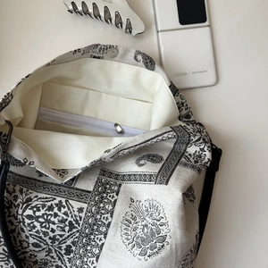 Detail of paisley canvas tote bag showing inner zipper pocket and black shoulder strap