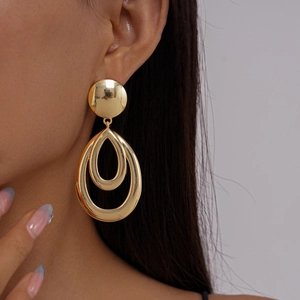 Detail view of large hollow geometric gold earrings on a model with natural lighting