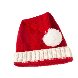Detailed close-up of a red knitted Christmas hat with soft white pompom and ribbed cuff