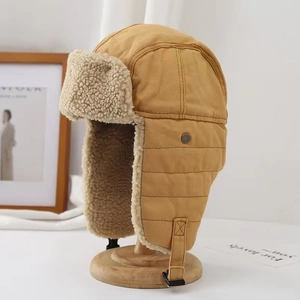 Khaki aviator hat with faux shearling lining and goggles on a wooden display stand