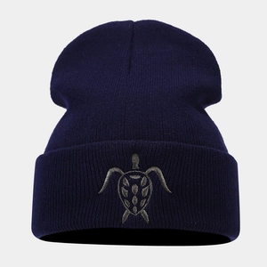 Detailed close-up of navy blue knit beanie featuring high-quality turtle embroidery design
