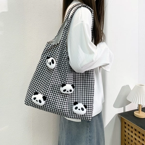 Close-up of black and white checkered canvas tote bag with 3D panda plush decorations
