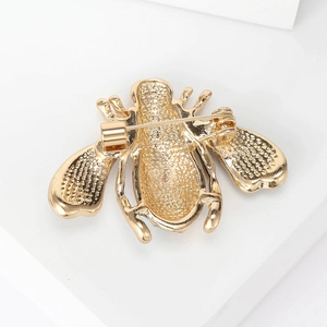 Golden alloy bee brooch showing secure back pin clasp and textured metal surface on white