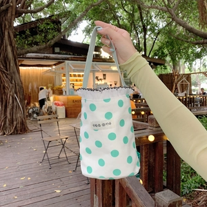 Close-up of canvas bucket bag featuring mint green polka dots and woven label