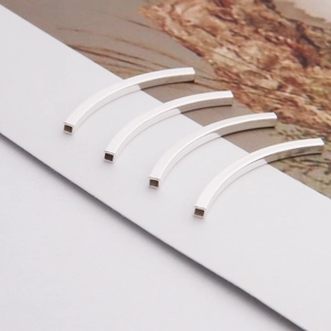 Macro detail of four polished silver S925 curved square tube beads for DIY jewelry making
