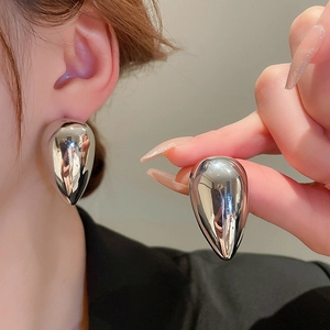 Close-up of polished silver drop earrings featuring a high-gloss metallic mirror finish