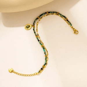 Detail of double-layer stainless steel bracelet with green beads and oval stone charm