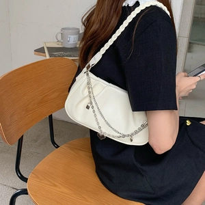 Detail of white pleated shoulder bag with woven strap and silver heart chain charm