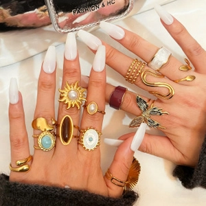 Close-up of golden multi-piece ring set with sun, pearl, and butterfly motifs on hand