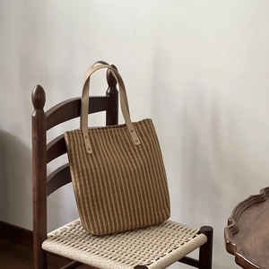 Vintage brown striped canvas tote bag with leather handles on a retro wicker chair