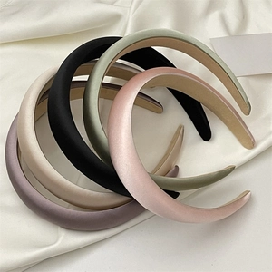 Close-up of assorted padded satin headbands in pastel colors on white silk background