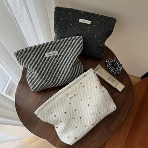 Detail of minimalist woven fabric makeup bags in black, grey, and cream with polka dots