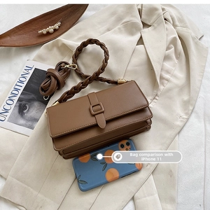Brown leather crossbody bag with woven handle shown next to iPhone 11 for size reference