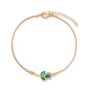 Detail of gold snake chain bracelet with blue tulip pendant and green crystal leaves