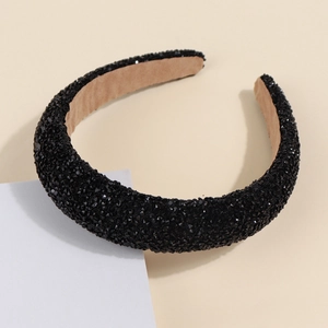 Detailed view of a black knotted headband with shimmering crystals on a white pedestal