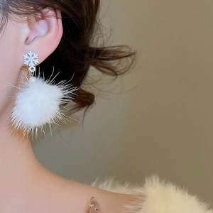 Primo piano di una modella che indossa eleganti orecchini a fiocco di neve con pompon
