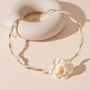Detail shot of a white fabric rose necklace with intertwined pearls on a gold chain
