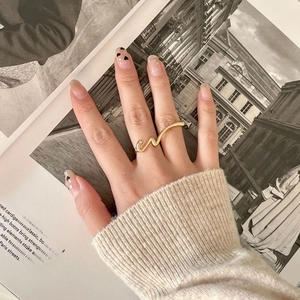 Close-up of a 925 sterling silver wavy gold ring worn on a finger for a minimalist chic look